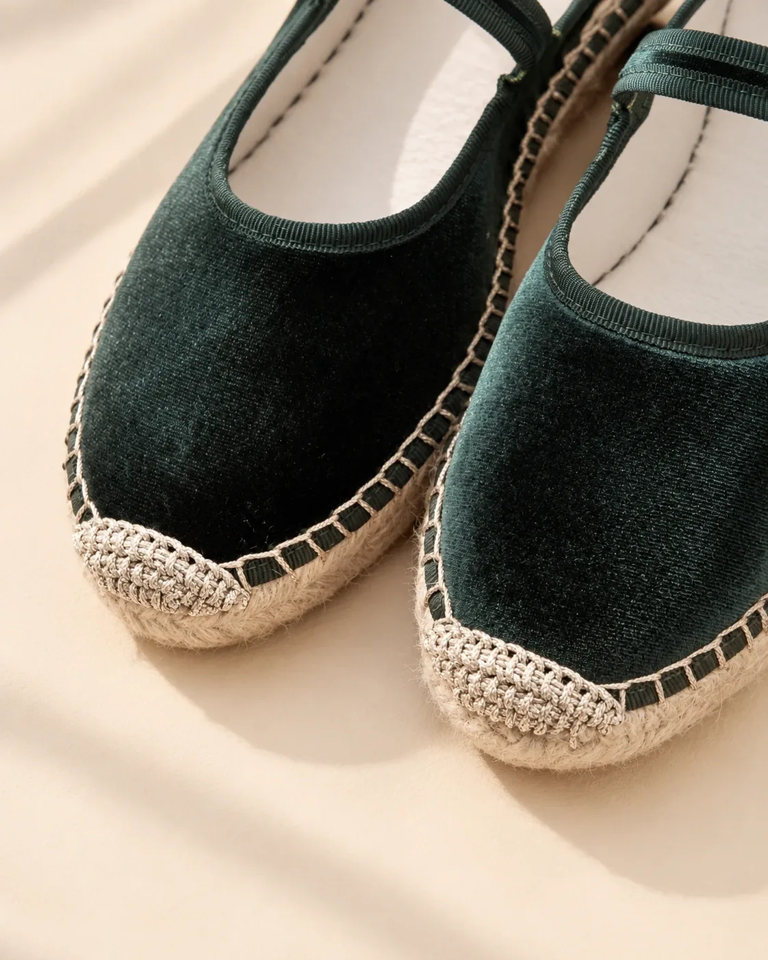 Close-up of two dark green velvet Mary Janes: matching edging, visible stitching on the jute sole and crochet detail on the toe.