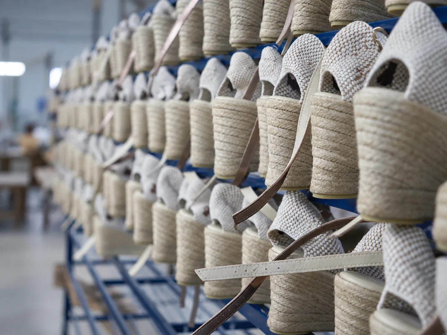 Canvas wedge espadrilles lined up on workshop racks before the final finishing.