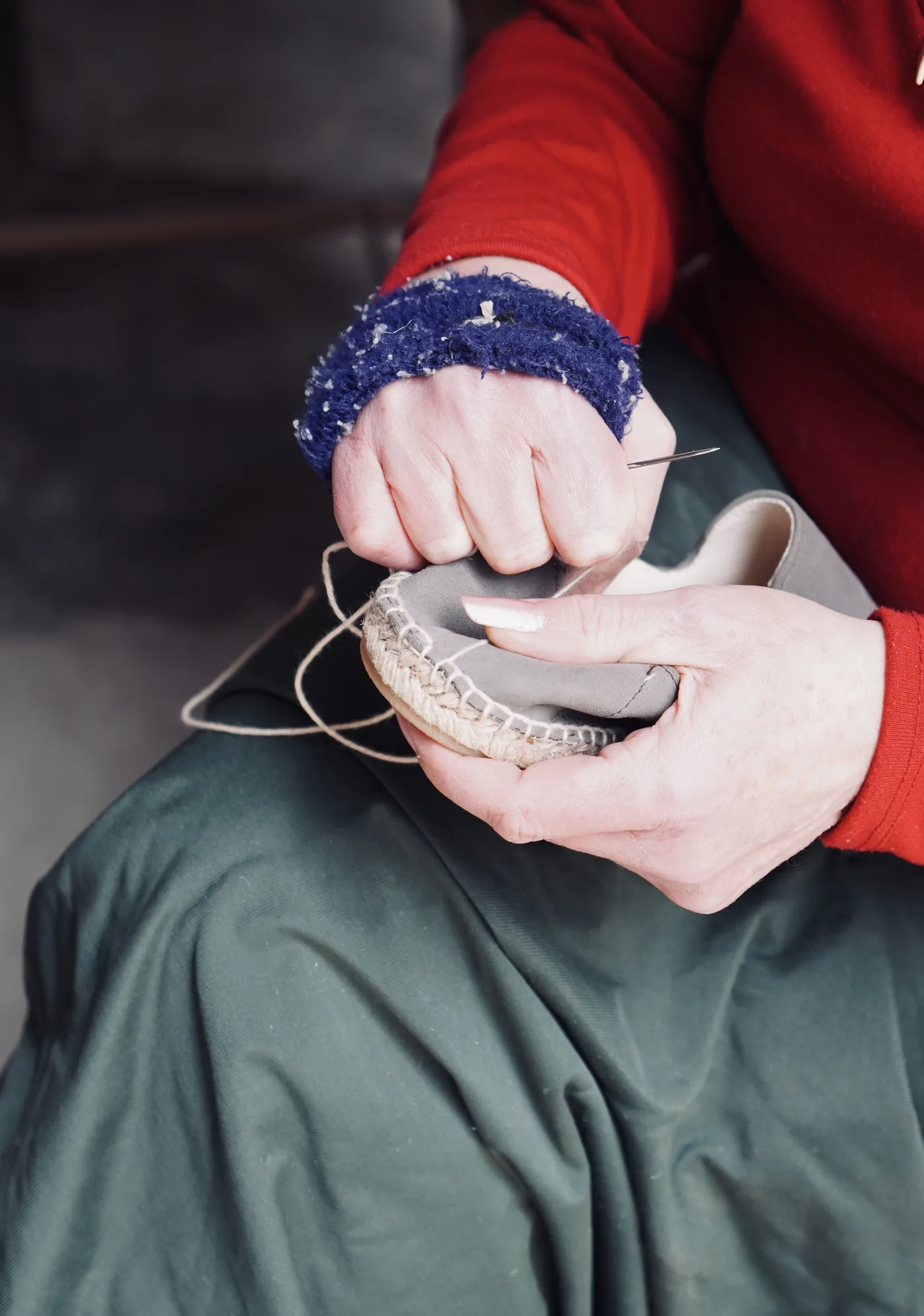 Hands stitching the edge of an espadrille by hand in the workshop.