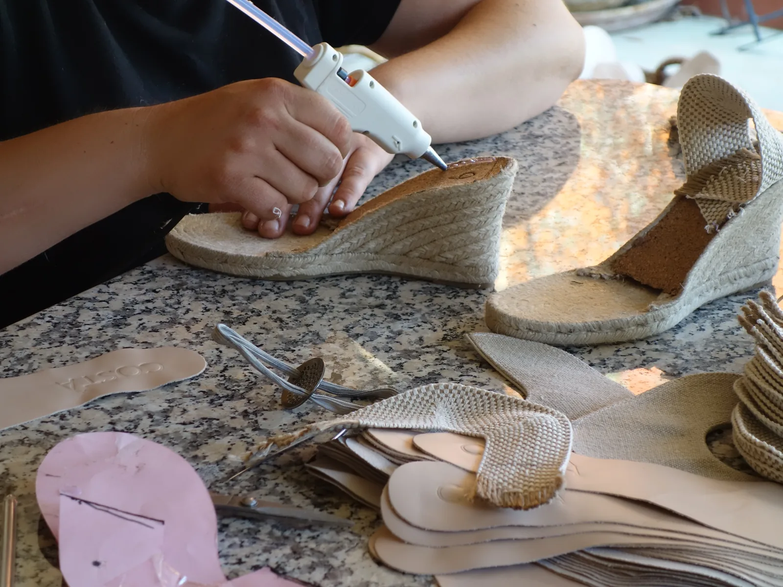 A wedge sandal being assembled on a workshop table.