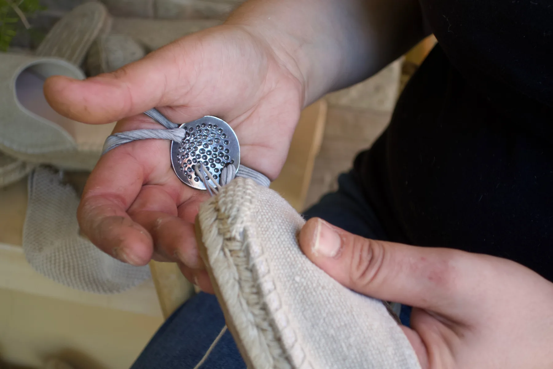 Close-up of hands, thread and stitching between the upper and the sole.